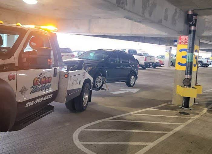 A G-Man Towing truck assisting a stranded vehicle on the roadside in DFW Airport, TX